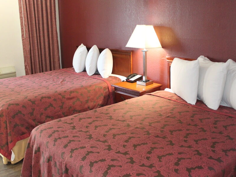 Hotel room with two double beds featuring red patterned bedspreads and white pillows