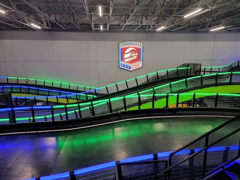 Indoor go-kart track with elevated curves and neon green lighting at Andretti.
