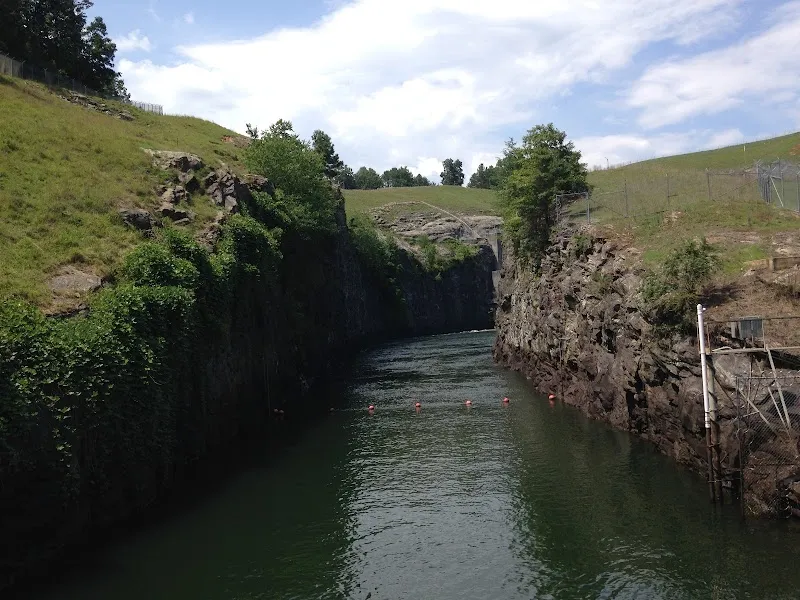 Water channel cutting through rocky cliffs with grassy hills at Buford Dam Park